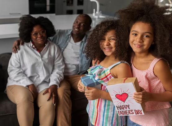A happy family on a couch with a Father's Day card and gift box.