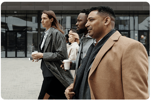 Three people walking down the street, holding cups of coffee.