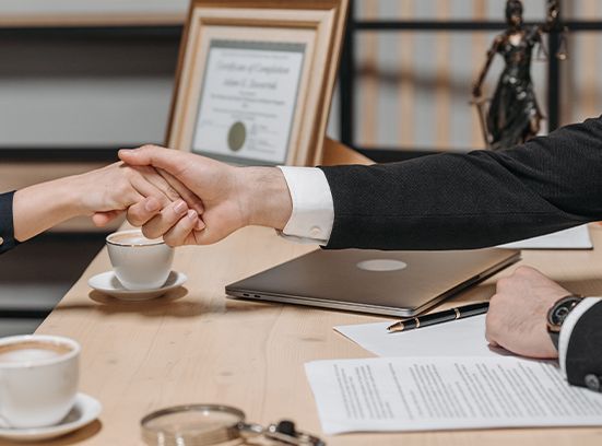 Businessman and businesswoman shaking hands across a desk.